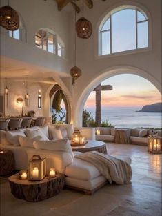 a living room filled with lots of furniture next to an ocean front window covered in candles