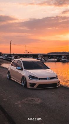 a white car parked next to the water at sunset