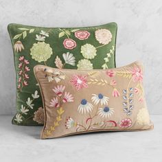 two green and pink pillows with floral designs on them, one is made out of velvet