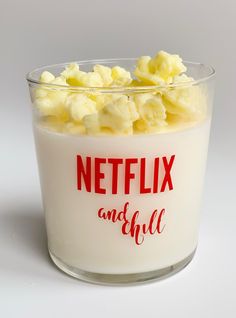 a glass bowl filled with popcorn sitting on top of a white table next to a red netflix logo