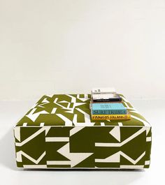 a green and white ottoman with books on it