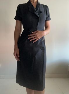 This dress is classic, and it has a beautiful fit. I sourced this is San Francisco. It's in perfect condition, not a button out of place. I believe the dress is 100% cotton. Please reach out with any questions.  Measurements Shoulder: 14 inches Sleeve length: 7 inches  Waist: 13 inches Hip: 18.5 inches Length: 42 inches Bottom opening: 22 inches PLEASE READ MEASUREMENTS *All items are measured flat. Measurements are not doubled.* EXCHANGE/STORE CREDIT ONLY Please view return policy DISCLOSURE Some items have been professionally cleaned and altered. Photos and measurements reflect the current state of the item. All additional care is the responsibility of the buyer. Fitted Midi Dress With Button Closure For Work, Fitted Midi Dress With Covered Buttons For Work, Fitted Vintage Dress For Semi-formal Occasions, Black Dress With Side Buttons For Work, Black Dresses With Side Buttons For Work, Black Workwear Dress With Side Buttons, Fitted Office Lady Dress With Buttons, Fitted Vintage Short Sleeve Dress For Work, Classic Fitted Shirt Dress With Covered Buttons