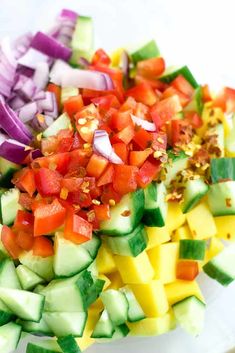 chopped vegetables are arranged on a plate to make a colorful salad with onions, peppers, and cucumbers