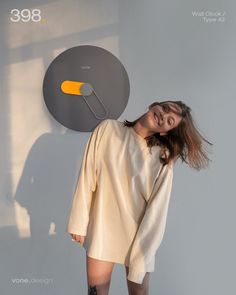 a woman standing in front of a wall with a clock on it's side