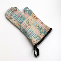 an oven mitt with flowers and checkered fabric on the front, sitting on a white surface