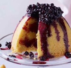 a bundt cake with blueberries and sauce on top is shown in a glass dish