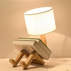 a lamp that is sitting on top of a table with a book in the shape of a stand