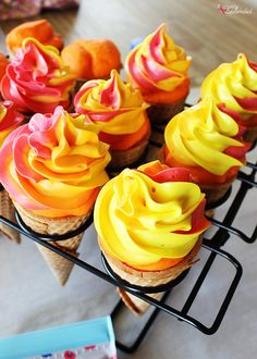 cupcakes with yellow and red frosting sitting on a wire rack