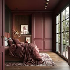 a bedroom with red walls and wooden floors, along with a large bed covered in a maroon blanket