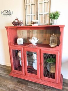 an old red hutch with glass doors and birdcage