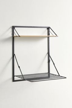 a metal shelf with two shelves on the top and one shelf below it, against a white wall