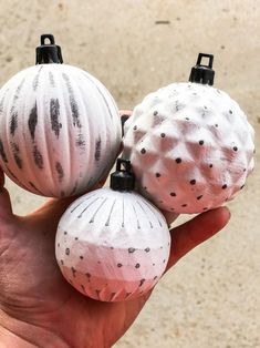 two white and black ornaments in the palm of someone's hand, with dirt on them