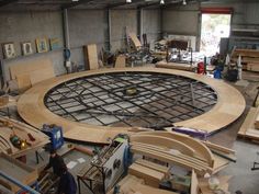 a large circular wooden table being built in a building with lots of work on it