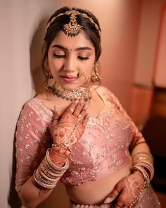 a woman in a bridal outfit is holding her hands together and posing for the camera