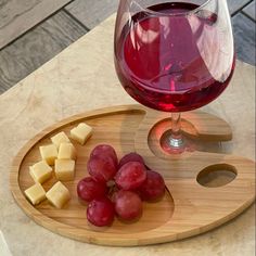 a glass of wine and some cheese on a wooden tray