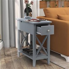 a grey end table with drawers and a vase on it in front of a couch