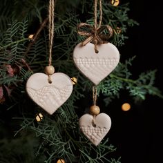 two ceramic heart ornaments hanging from a christmas tree