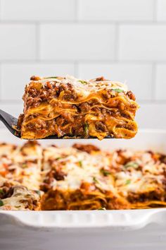 a spoon full of lasagna casserole being lifted from a baking dish