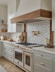 an image of a kitchen setting with white cabinets and gold pulls on the oven hood