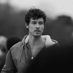 black and white photograph of a young man with curly hair wearing a hoodie looking at the camera