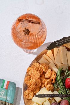 a plate full of cheese, crackers and fruit next to a glass of wine