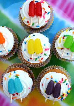 cupcakes with popsicles and sprinkles are arranged on a plate