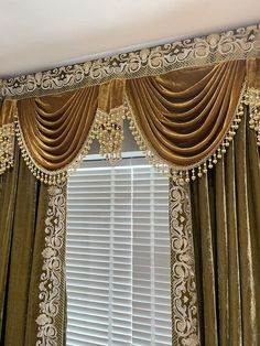 a window with gold curtains and chandelier hanging from it's valance