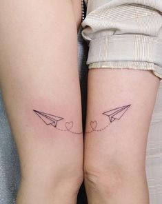 two people with matching tattoos on their legs, one has an airplane and the other has hearts