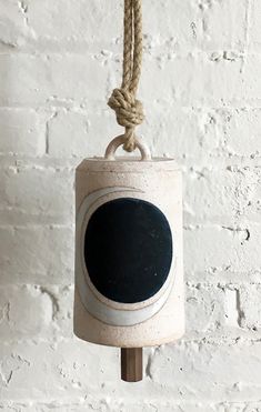 a chalkboard hanging from a rope in front of a white brick wall with a black circle on it