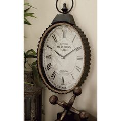 a clock is hanging on the wall next to a potted plant and an iron cross