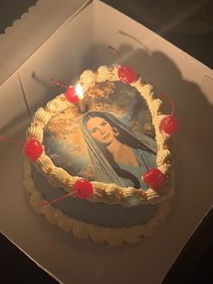 a cake in a box with an image of the virgin mary on it and candles