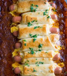 a casserole dish filled with cheese and hot dogs on top of chili sauce