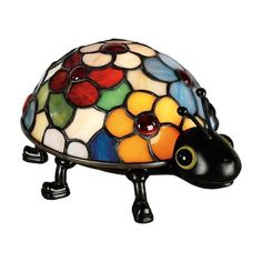 a lamp that is sitting on top of a turtle shaped table cloth holder with flowers and leaves painted on it