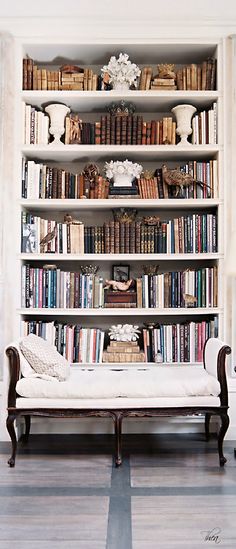 a white couch sitting in front of a book shelf filled with books