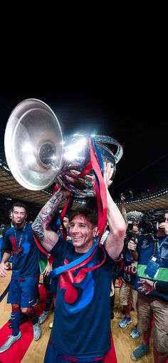 a man holding up a trophy while standing on top of a basketball court at night