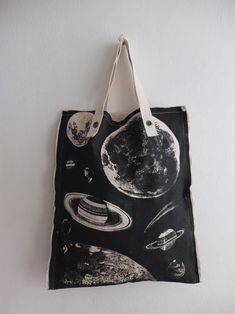 a black and white tote bag hanging on a wall with planets printed on it