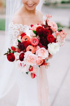 a bride holding a bouquet of red and white flowers