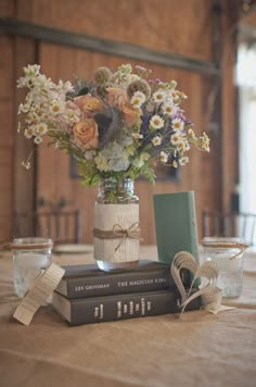 flowers in a vase on top of two books sitting on a table next to each other