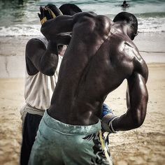 two men standing on the beach with their backs to each other