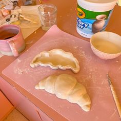 some food is laying out on a pink counter top next to a cup and spoon