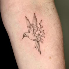 a bird with flowers on it's wings is shown in black and grey ink