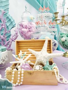 an assortment of seashells and starfish in a wooden box on a table