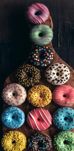 there are many different donuts on the wooden tray with sprinkles in them