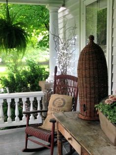 the porch is decorated with wicker furniture and flowers on it, along with an old rocking chair