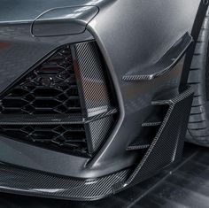 the front end of a black sports car with carbon fiber and chrome finish on it