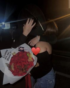 a man and woman hug each other while holding flowers in their hands at night time