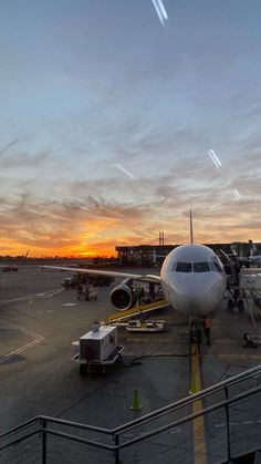 an airplane is parked on the tarmac at sunset