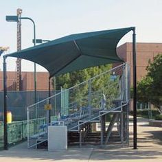 an outdoor baseball cage with stairs and railings on the side of the field in front of a building