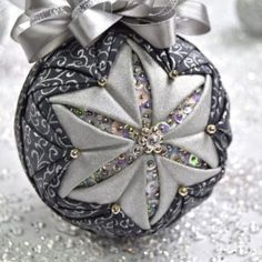 a silver ornament with a bow on it's top and glittery background