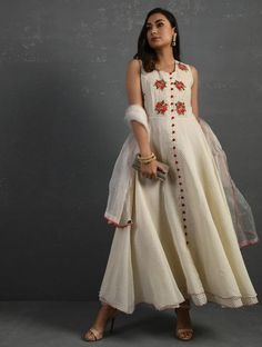 A double-layered umbrella cut front open Chanderi kurta with all-over floral buttis in yoke made using beads, sequins and silk French knots. Beadwork runs along the neckline and armhole. Contrast buttons and scalloped edges embroidered double layered flared hemline. The kurta comes with a delicate chanderi dupatta with all over sequence work and a wide woven zari border at the hem. Kurta measurements (in Inches): Size S: Bust - 38", Waist - 35", Length: 52" Size M: Bust - 40", Waist - 37", Lengt Embroidered Anarkali Set For Summer, Embroidered Summer Anarkali Set, Summer Embroidered Anarkali Set, Summer Anarkali Set With Floral Embroidery, Festive Embellished Off White Sets, Festive Off White Embellished Sets, Festive Off-white Embellished Sets, Chanderi Sleeveless Dresses For Festivals, White Embroidered Dress With Zari Work For Festive Occasions